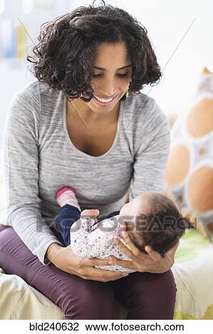 Stock Image - Hispanic mother cradling baby daughter. Fotosearch