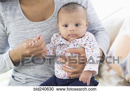 Stock Image - Hispanic mother holding baby daughter. Fotosearch