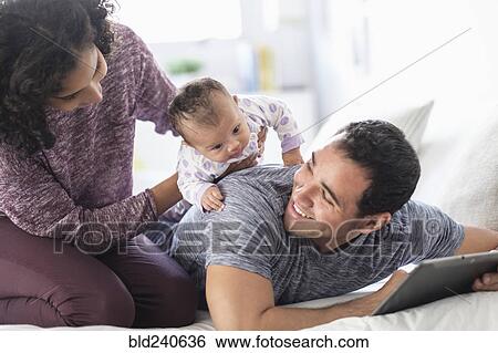 Stock Photograph - Hispanic mother holding baby daughter on back of father. Fotosearch
