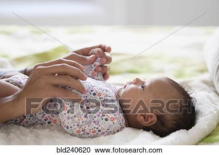 Hispanic mother holding hands with baby daughter on bed View Large Photo Image Stock Image - Hispanic mother holding hands with baby daughter on bed. Fotosearch