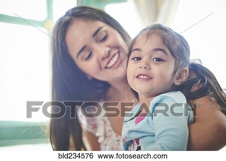 Hispanic mother holding smiling daughter View Large Photo Image Stock Photograph - Hispanic mother holding smiling daughter. Fotosearch