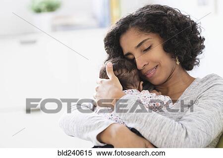 Stock Photography - Hispanic mother hugging baby daughter. Fotosearch