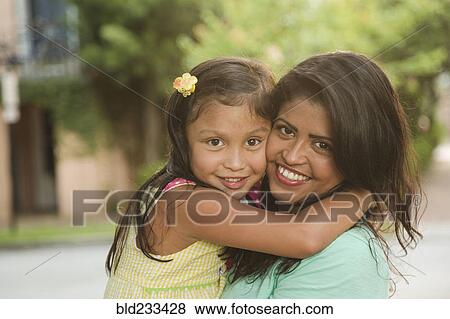 Stock Photo - Hispanic mother hugging daughter. Fotosearch