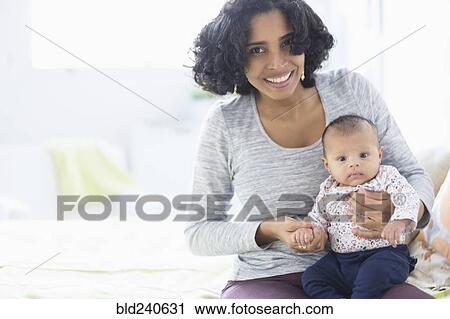 Stock Image - Hispanic mother posing with baby daughter. Fotosearch