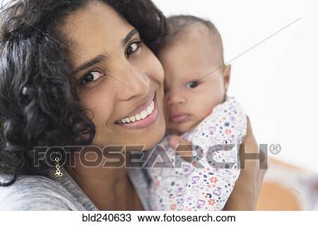 Stock Image - Hispanic mother posing with baby daughter. Fotosearch
