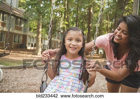 Hispanic mother pushing daughter in playground swing View Large Photo Image Stock Image - Hispanic mother pushing daughter in playground swing. Fotosearch