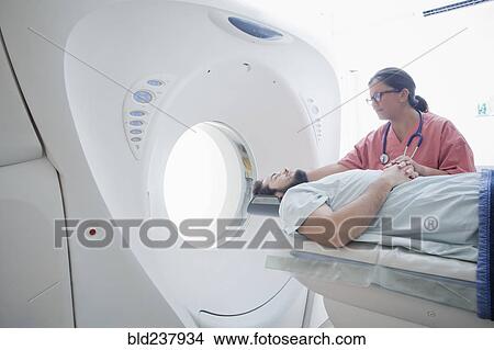 Picture - Hispanic nurse comforting patient at scanner. Fotosearch