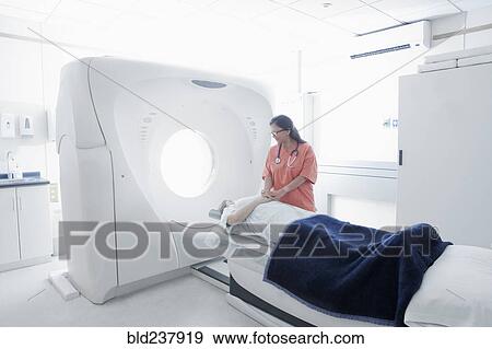 Stock Photo - Hispanic nurse comforting patient at scanner. Fotosearch