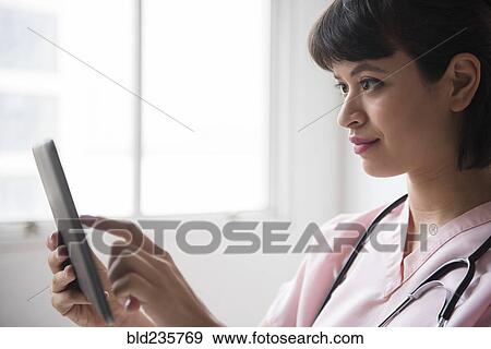 Stock Photo - Hispanic nurse using digital tablet. Fotosearch