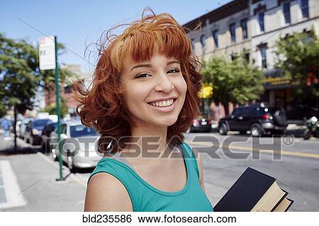 Hispanic woman carrying books on city sidewalk View Large Photo Image Stock Photograph - Hispanic woman carrying books on city sidewalk. Fotosearch