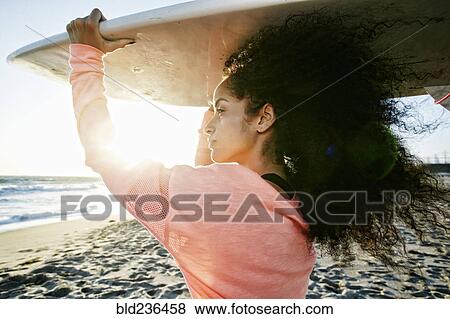 Hispanic woman holding surfboard at beach View Large Photo Image Stock Photo - Hispanic woman holding surfboard at beach. Fotosearch