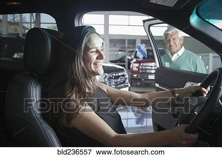 Hispanic woman sitting in car in dealership showroom View Large Photo Image Stock Photo - Hispanic woman sitting in car in dealership showroom. Fotosearch