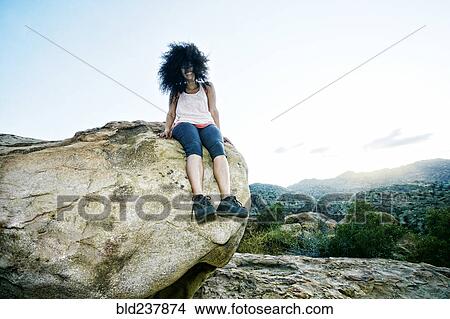 Hispanic woman sitting on boulder in wind View Large Photo Image Picture - Hispanic woman sitting on boulder in wind. Fotosearch