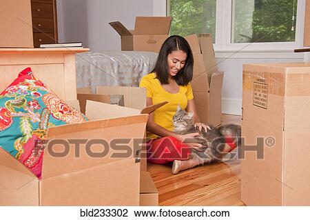 Hispanic woman sitting on floor petting cat near moving boxes View Large Photo Image Stock Image - Hispanic woman sitting on floor petting cat near moving boxes. Fotosearch
