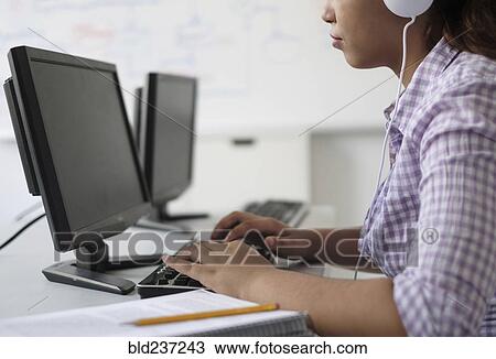 Stock Image - Hispanic woman typing in computer lab. Fotosearch