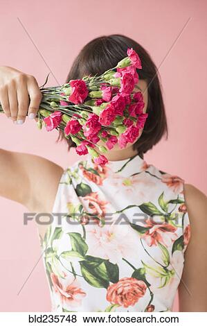 Stock Photo - Hispanic woman wearing floral dress holding flowers. Fotosearch