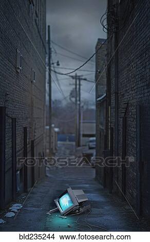 Picture - Illuminated broken monitor in city alley. Fotosearch