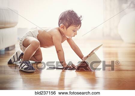 Indian baby boy crawling on floor with digital tablet View Large Photo Image Stock Photograph - Indian baby boy crawling on floor with digital tablet. Fotosearch