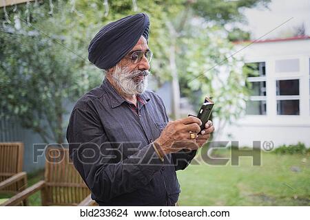 Picture - Indian man texting on cell phone. Fotosearch
