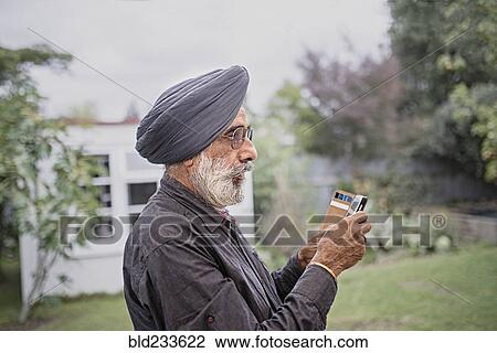 Stock Image - Indian man texting on cell phone. Fotosearch