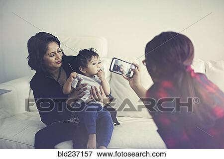 Indian woman photographing mother and son with cell phone View Large Photo Image Stock Photo - Indian woman photographing mother and son with cell phone. Fotosearch