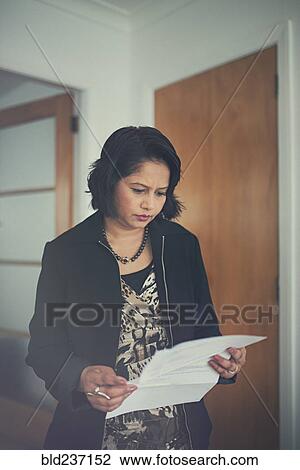 Stock Image - Indian woman reading paperwork. Fotosearch