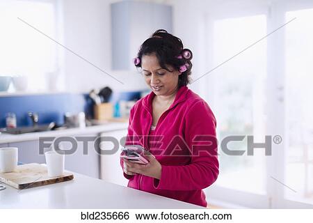 Indian woman wearing hair curlers texting on cell phone View Large Photo Image Stock Photograph - Indian woman wearing hair curlers texting on cell phone. Fotosearch