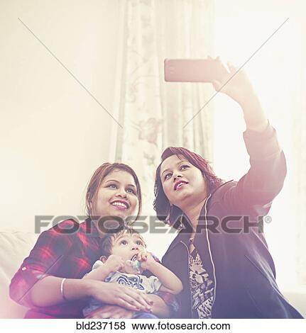 Indian women posing for cell phone selfie with baby boy View Large Photo Image Stock Photo - Indian women posing for cell phone selfie with baby boy. Fotosearch