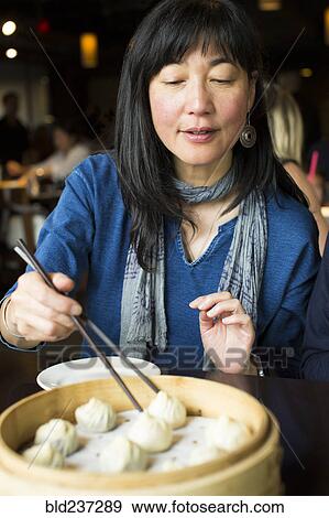 Japanese woman eating food with chopsticks View Large Photo Image Stock Photo - Japanese woman eating food with chopsticks. Fotosearch