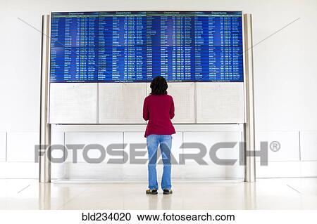 Stock Image - Japanese woman reading departure schedules at airport. Fotosearch