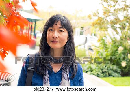 Stock Photo - Japanese woman smiling near autumn leaves. Fotosearch