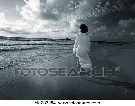 Picture - Japanese woman walking on beach. Fotosearch