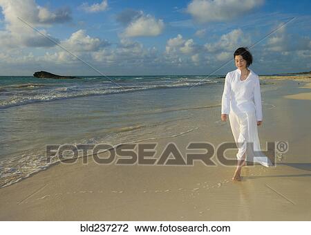 Stock Image - Japanese woman walking on beach. Fotosearch