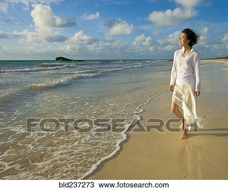 Stock Image - Japanese woman walking on beach. Fotosearch