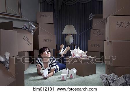 Stock Image - Korean woman eating take-out in new home. Fotosearch