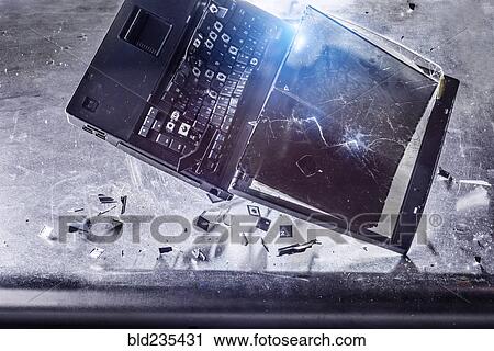 Stock Image - Laptop falling and shattering on desk. Fotosearch