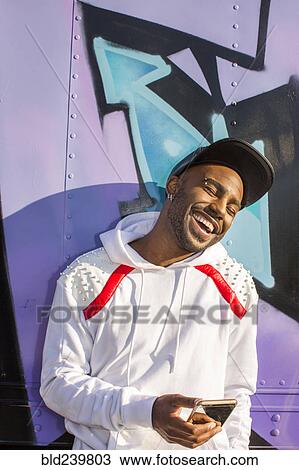 Stock Image - Laughing Black man texting on cell phone. Fotosearch