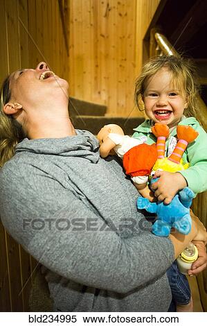 Stock Photography - Laughing Caucasian mother holding daughter. Fotosearch