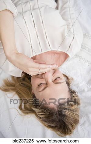 Stock Photography - Laughing Caucasian woman laying on bed. Fotosearch
