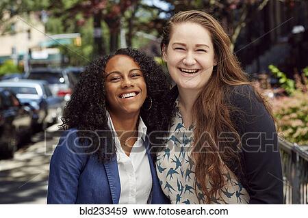 Stock Photo - Laughing friends posing on city sidewalk. Fotosearch