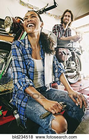 Laughing man and woman repairing motorcycle in garage View Large Photo Image Stock Photo - Laughing man and woman repairing motorcycle in garage. Fotosearch
