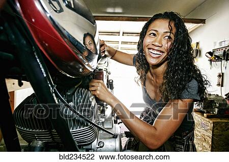 Laughing Mixed Race woman repairing motorcycle in garage View Large Photo Image Stock Image - Laughing Mixed Race woman repairing motorcycle in garage. Fotosearch