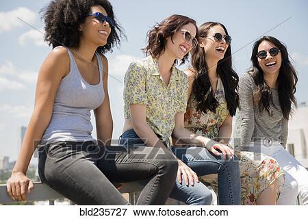 Laughing women sitting on railing outdoors View Large Photo Image Stock Photo - Laughing women sitting on railing outdoors. Fotosearch