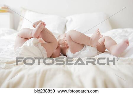 Legs of Caucasian twin baby girls laying on bed View Large Photo Image Stock Image - Legs of Caucasian twin baby girls laying on bed. Fotosearch