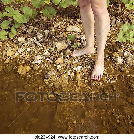 Picture - Legs of Caucasian woman standing on shore of lake. Fotosearch