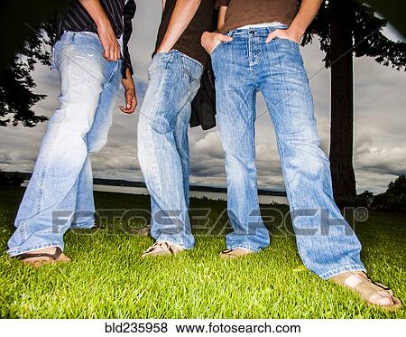 Legs of friends wearing jeans in grass View Large Photo Image Stock Photo - Legs of friends wearing jeans in grass. Fotosearch
