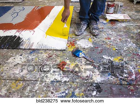 Stock Photography - Legs of Mari man painting canvas on floor. Fotosearch