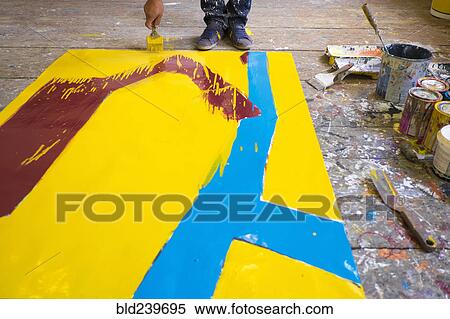 Stock Photography - Legs of Mari man painting canvas on floor. Fotosearch
