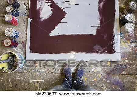 Stock Photo - Legs of Mari man standing near paint cans and canvas on floor. Fotosearch