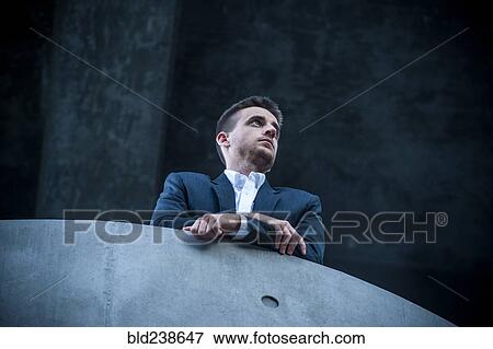 Stock Photo - Low angle view of businessman leaning on balcony. Fotosearch